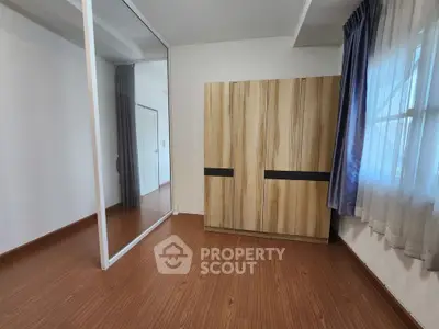 Spacious bedroom with wooden flooring and large mirrored wardrobe