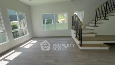 Spacious modern living room with large windows and elegant staircase