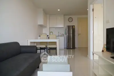 Modern open-plan living room and kitchen with sleek furniture and stainless steel appliances.