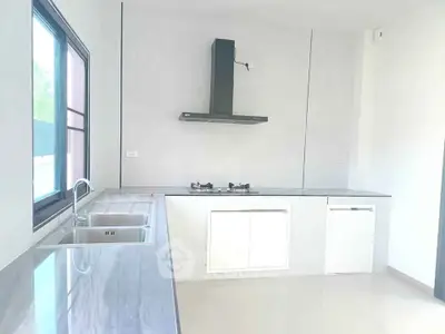 Modern kitchen with sleek countertops and gas stove in a bright, minimalist design.