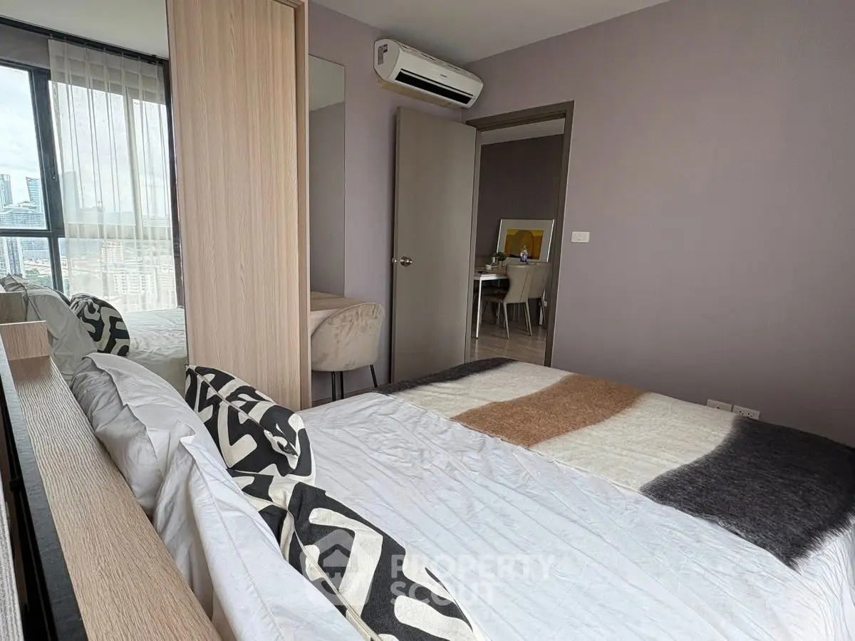 Modern bedroom with city view, stylish decor, and air conditioning in urban apartment.