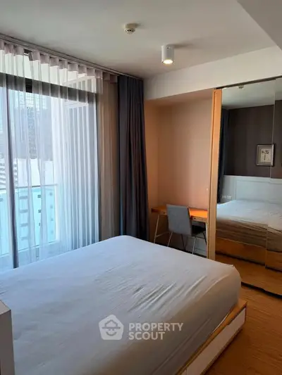 Modern bedroom with large window and city view, featuring a cozy bed and stylish desk area.