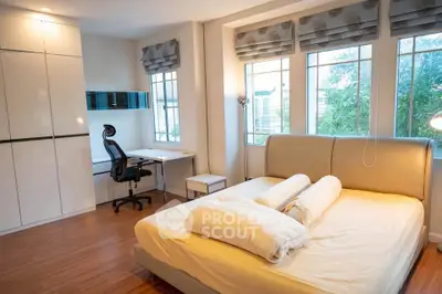 Spacious bedroom with modern furniture and large windows offering natural light.