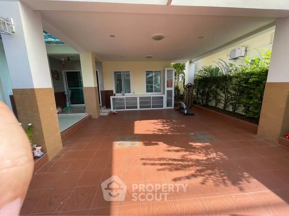 Spacious covered patio with exercise equipment and greenery, perfect for outdoor relaxation and activities.