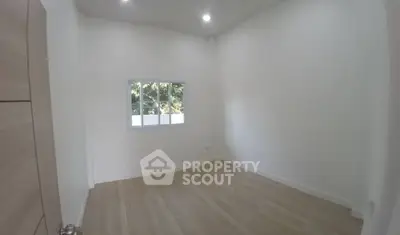Spacious empty room with large window and modern flooring, perfect for customization.