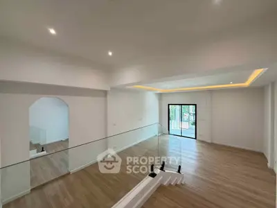 Spacious modern living room with glass railing and wooden flooring