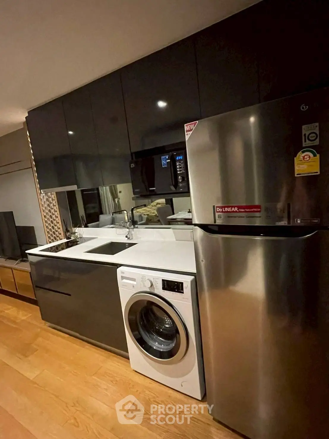 Modern kitchen with sleek cabinets, stainless steel fridge, and built-in washing machine.