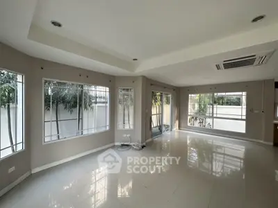 Spacious modern living room with large windows and tiled flooring