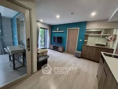 Modern living room with open kitchen and balcony access, featuring sleek design and natural light.