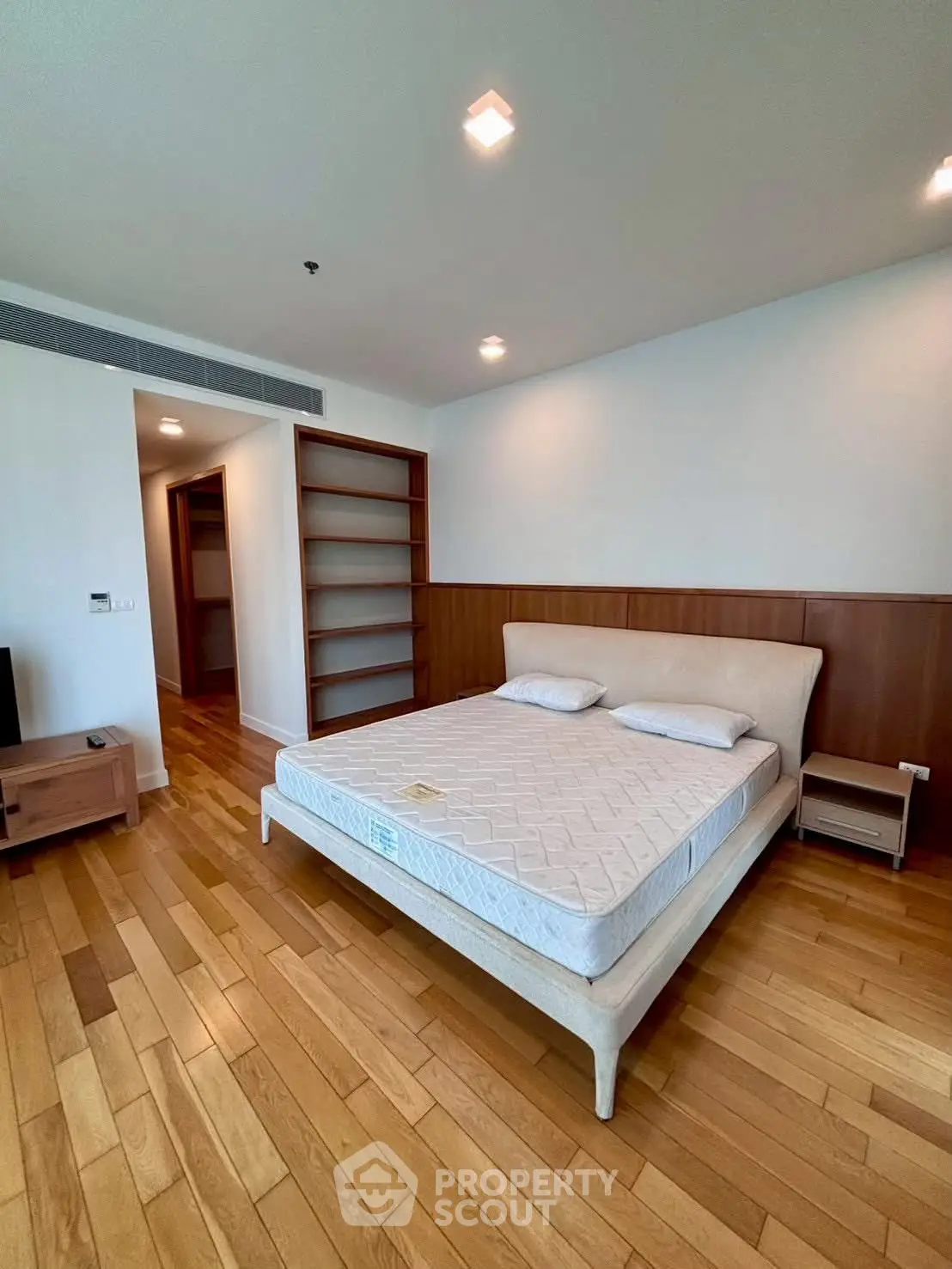 Spacious bedroom with wooden flooring and modern furnishings in a luxury apartment.