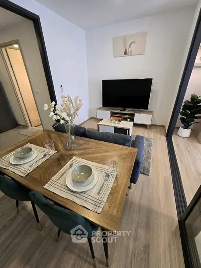 Modern living room with stylish dining area and TV setup, featuring elegant decor and wooden flooring.