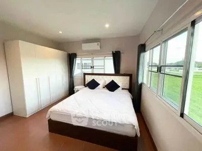Spacious bedroom with large windows and scenic view, featuring modern furniture and ample natural light.