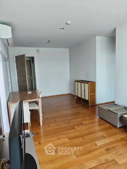 Spacious living room with wooden flooring and modern furniture in a bright apartment.