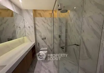 Luxurious modern bathroom with marble tiles and glass shower enclosure