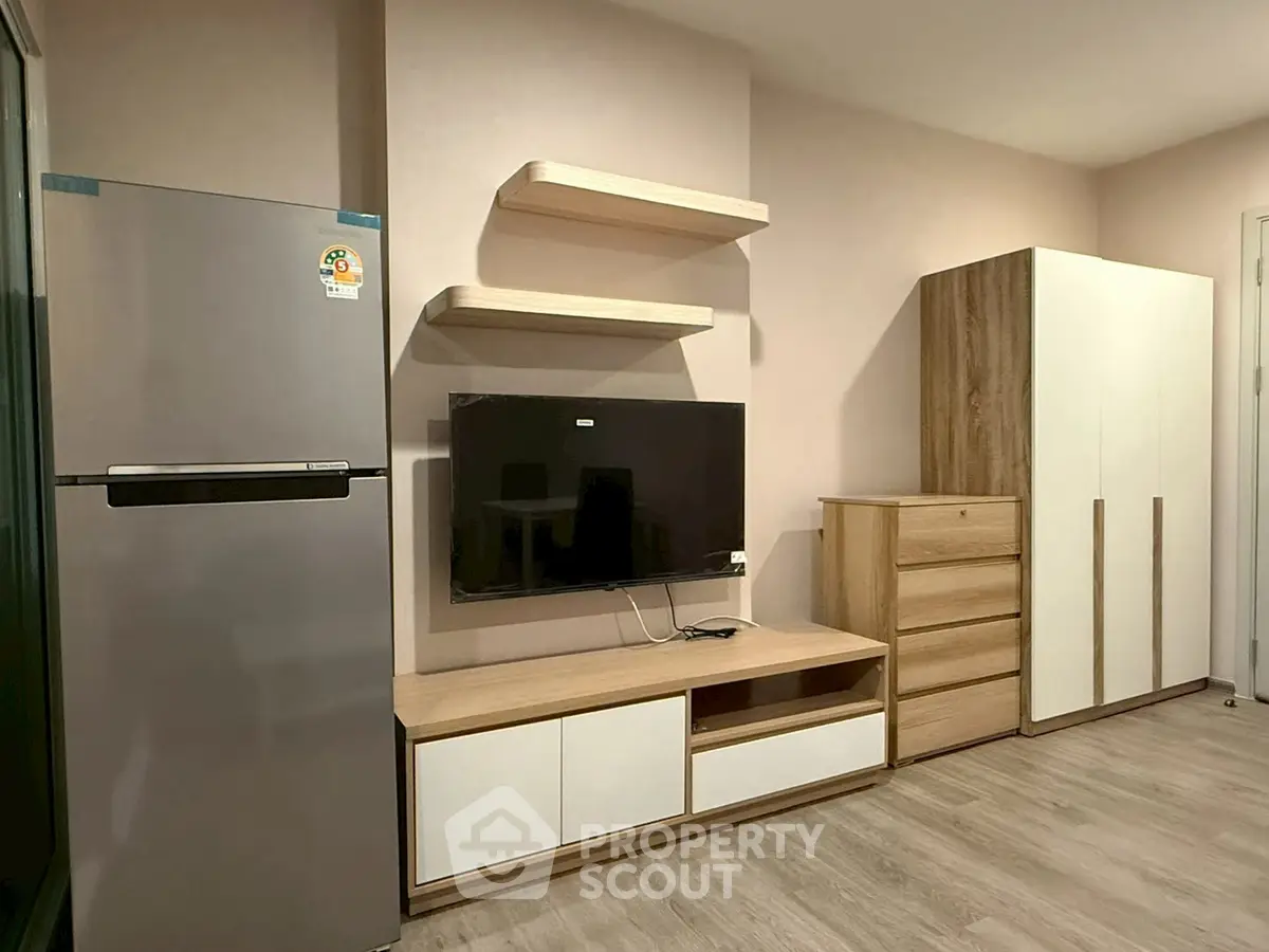 Modern living room with sleek furniture and appliances, featuring a mounted TV and spacious storage solutions.