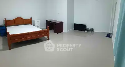 Spacious bedroom with wooden bed frame and desk, ideal for comfort and productivity.