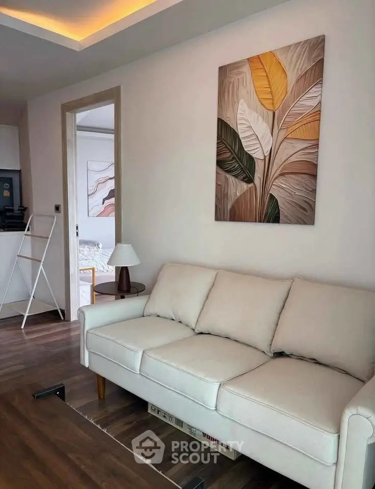 Modern living room with stylish decor and comfortable sofa, featuring elegant wall art and wooden flooring.