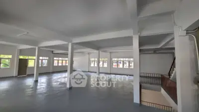 Spacious open-plan interior with large windows and staircase, ideal for versatile use.