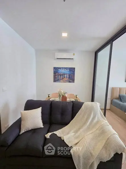 Modern living room with cozy sofa and elegant dining area in open layout apartment.