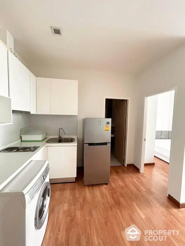 Modern kitchen with washing machine and fridge in compact layout