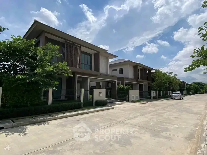 Modern suburban homes with lush greenery and clear blue skies, showcasing contemporary architecture.