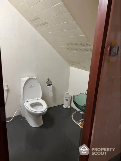 Cozy bathroom with modern toilet under sloped ceiling, perfect for compact spaces.