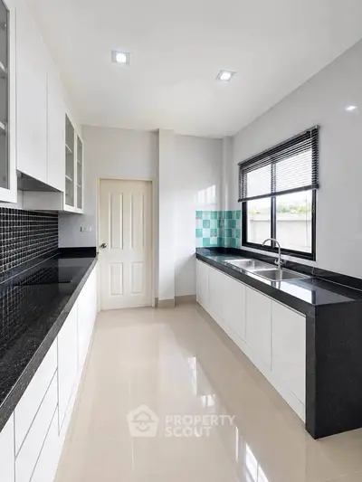 Sleek modern kitchen with black countertops and ample natural light
