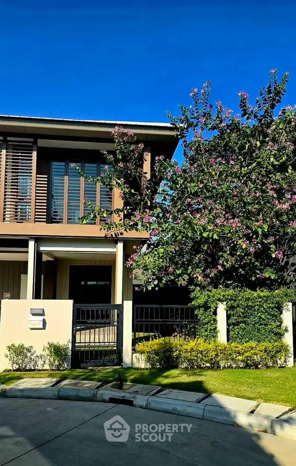 Modern two-story house with lush garden and driveway in a serene neighborhood.