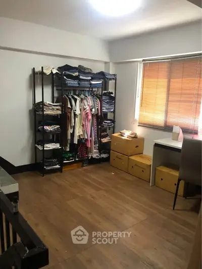 Spacious room with wooden flooring, organized shelving, and natural light from window blinds.