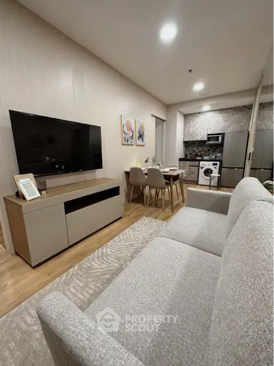 Modern living room with open kitchen, stylish decor, and cozy seating area