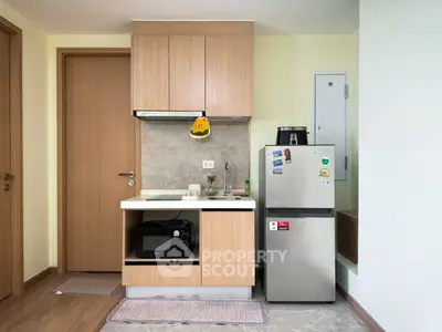 Compact modern kitchen with wooden cabinets and stainless steel appliances in cozy apartment.