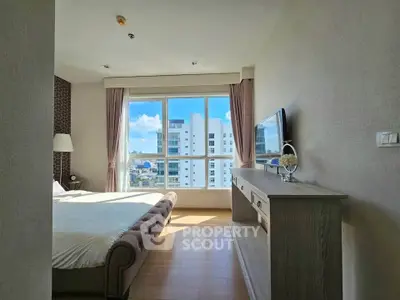 Spacious bedroom with large window offering stunning city views in modern apartment.