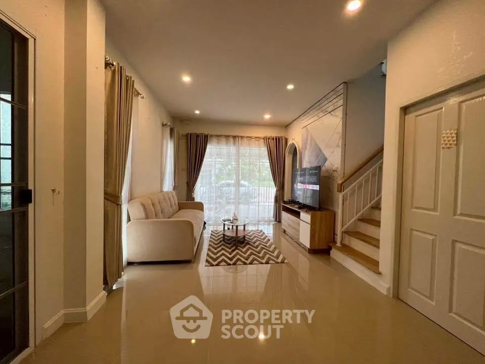 Spacious living room with modern decor and natural light, featuring a cozy sofa and stylish staircase.