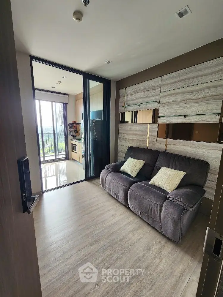 Modern living room with cozy sofa and open kitchen layout, featuring large windows with scenic view.