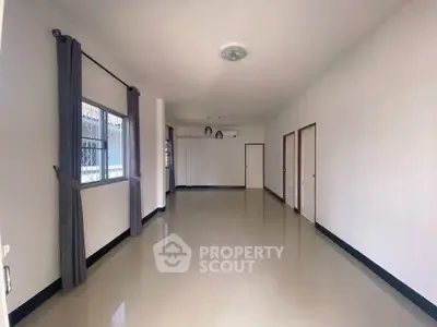 Spacious empty room with large window and tiled floor, ready for customization.