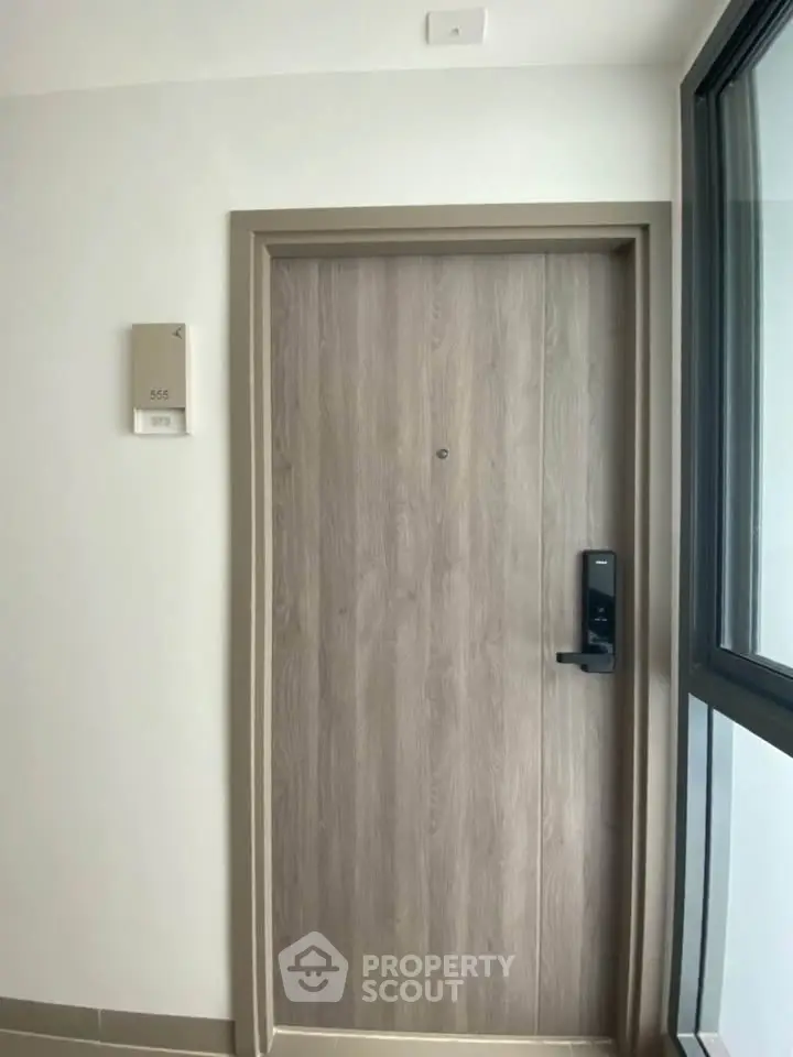 Modern apartment entrance with sleek wooden door and digital lock system.