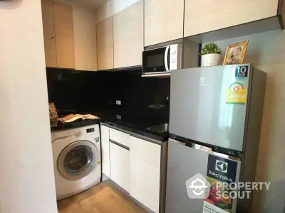 Modern kitchen with washing machine and Electrolux fridge in compact layout