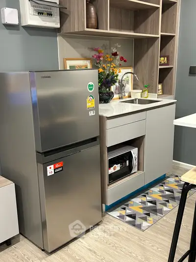 Modern compact kitchen with stainless steel fridge and built-in microwave