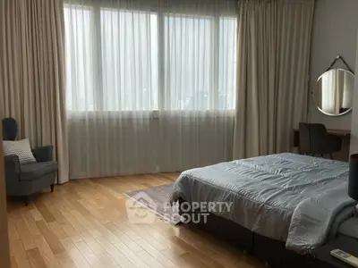 Spacious bedroom with large windows and cozy decor
