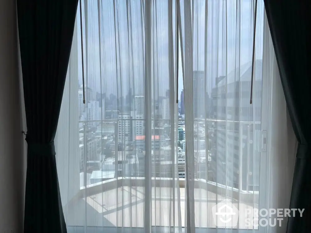 Stunning cityscape view from high-rise apartment balcony with sheer curtains