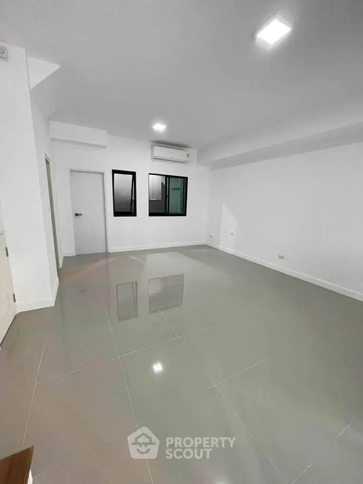 Spacious empty living room with modern tile flooring and air conditioning unit.