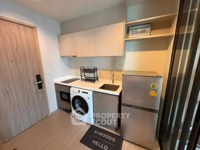 Modern compact kitchen with washing machine and fridge in stylish apartment.