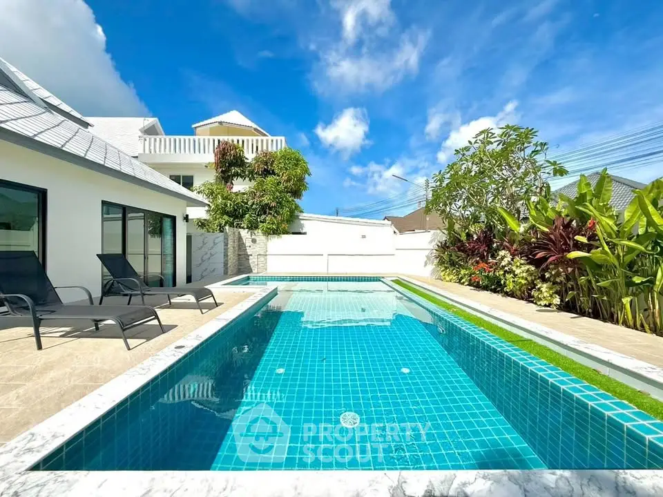 Luxurious villa with private pool and lush garden under clear blue sky.