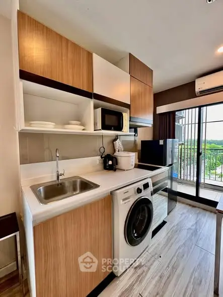 Modern kitchen with washing machine and microwave, featuring sleek cabinetry and balcony view.