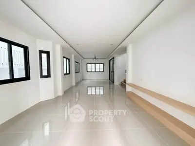Spacious modern living room with sleek tile flooring and ample natural light.