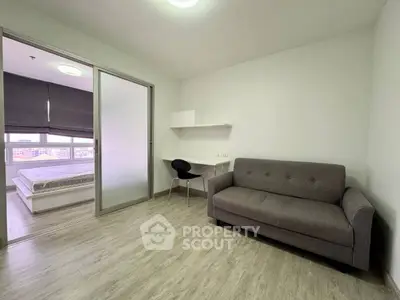 Modern apartment with cozy living room and bedroom, featuring sleek furniture and natural light.