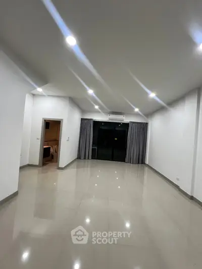 Spacious modern living room with glossy tiled floors and large windows.