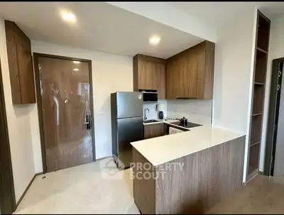 Modern kitchen with sleek wooden cabinets and stainless steel appliances in a cozy apartment.