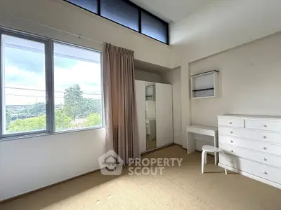 Bright bedroom with large window and minimalist furniture, offering serene views.