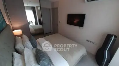 Cozy bedroom with modern decor and wall-mounted TV, perfect for relaxation.